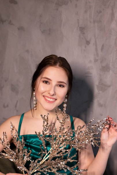 sexy attractive brunette woman in elegant green aquamarine dress with artificial branch with sparkly sequins. beautiful sensual girl - Foto, Imagem