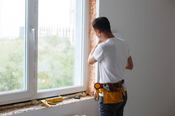 Homem colocando enchimento entre janela e parede em uma nova casa - Foto, Imagem