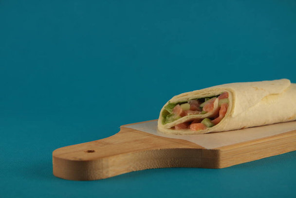 doner kebab on wooden cutting board against blue background. Image contains copy space - Foto, Bild