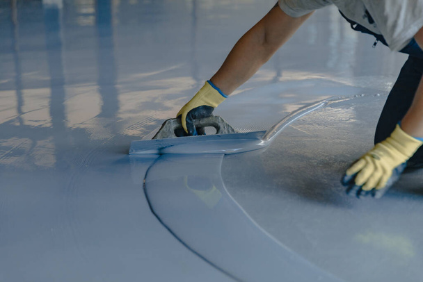 The worker applies gray epoxy resin to the new floor - Photo, Image