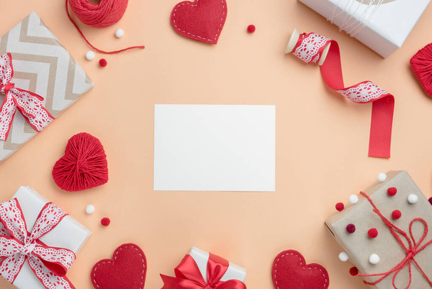 Valentinstag Komposition mit Geschenken und handgemachten Herzen auf beigem Hintergrund. Draufsicht mit leerer Karte für Text. - Foto, Bild
