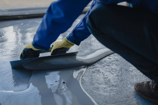 The worker applies gray epoxy resin to the new floor - Φωτογραφία, εικόνα