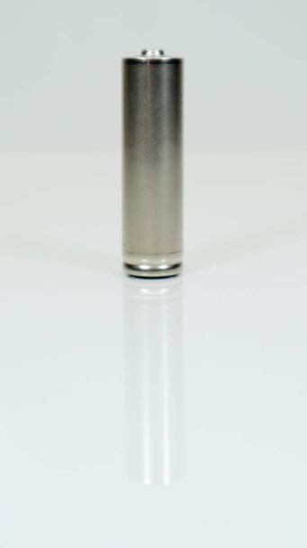 AA bateria recarregável alcalina em fundo branco brilhante com reflexão. Feche uma bateria vazia com espaço de cópia. Fotografia vertical - Foto, Imagem