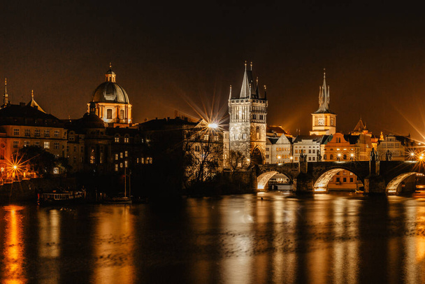 Карлов освещал Карлов мост, наиболее ярко отраженный в реке Влтаве. Вечерняя панорама Праги, Чехия. Длительное воздействие света города. Изумительный европейский город scape.Travel городской концепции - Фото, изображение