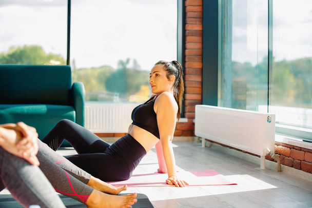 A brunette in sportswear is resting on a fitness mat during a workout. - Fotó, kép