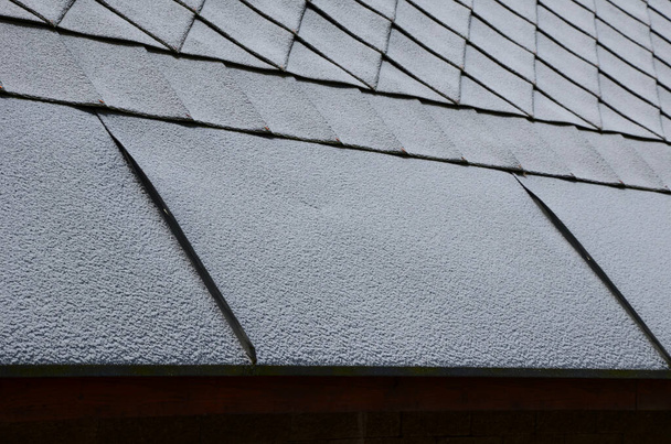 窓の正方形のスレートテンプレートとグレーの屋根のタイル。嘘をついてた。正方形のグリッドパターン。屋根の下の端は雪の層をはぎ取るための金属片で形成されています. - 写真・画像