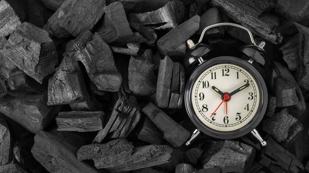 Reloj despertador retro negro sobre fondo de carbón negro con espacio para copiar. Vista superior - Foto, Imagen