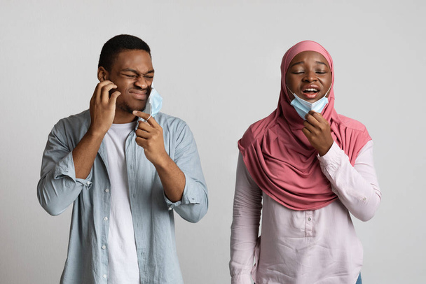 Sinirli Müslüman çift nefes almak için yüz maskelerini çıkarıyorlar. - Fotoğraf, Görsel