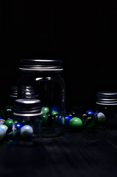 Jar with colored marbles on a black surface - Foto, imagen