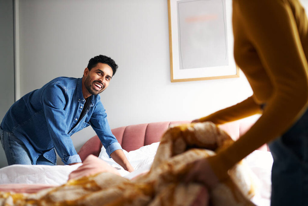 Casal jovem compartilhando prostitutas domésticas e fazendo cama em casa juntos - Foto, Imagem