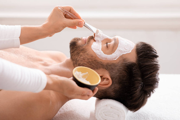 baard Kaukasische man het krijgen van gezichtsbehandeling bij spa salon - Foto, afbeelding