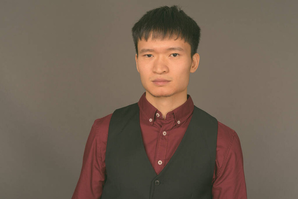 Fiatal kínai üzletember szürke háttérrel - Fotó, kép