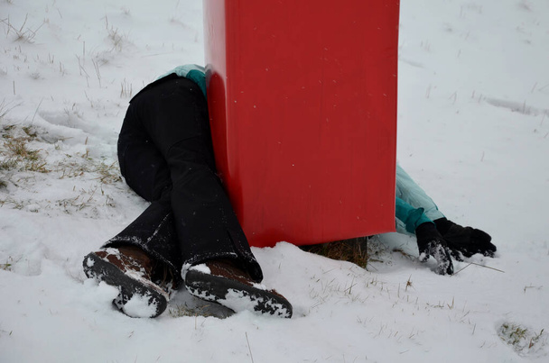 La donna si è schiantata ad alta velocità contro una barriera di schiuma su un palo vicino alla pista da sci. È ferita, ma salvata da un materasso protettivo rosso, una zona d'impatto. sdraiato sulla neve intorno al palo. - Foto, immagini
