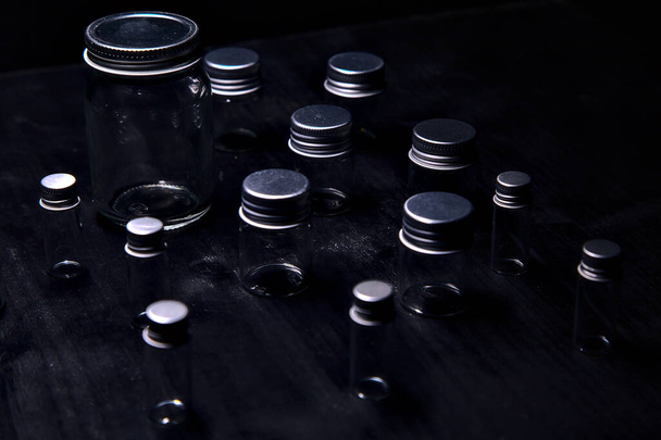 Empty tiny jars on a black surface - 写真・画像