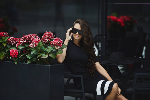 Beautiful, fashionable brunette model girl in black dress posing outdoors, spring - Fotografie, Obrázek