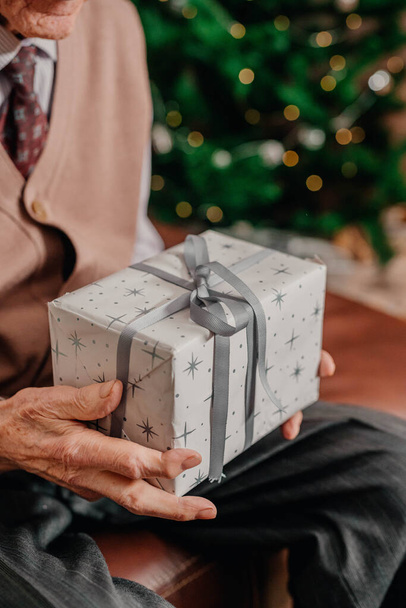 Senior hält Weihnachtsgeschenk in Händen - Foto, Bild
