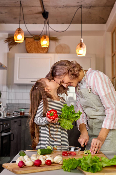 lovely mother and daughter kissing in the kitchen - Fotoğraf, Görsel