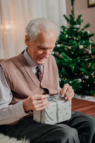 Uomo anziano che tiene regalo di Natale in mano a Natale - Foto, immagini