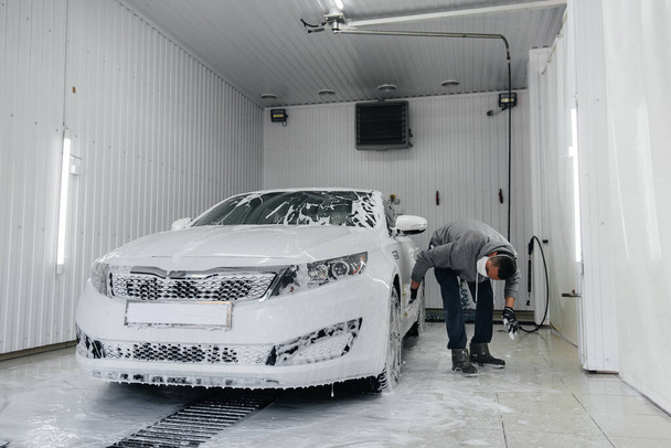 Modern washing with foam and high-pressure water of a white car. Car wash - Foto, afbeelding