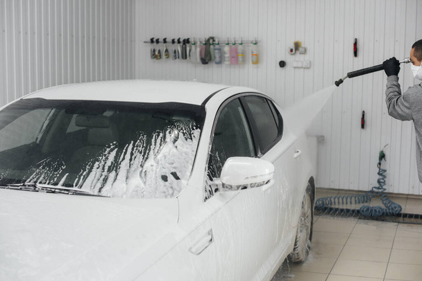 Modern washing with foam and high-pressure water of a white car. Car wash - Фото, изображение