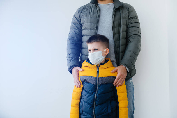 A father with his child stands in a mask during the quarantine. Pandemic, coronavirus - Фото, изображение