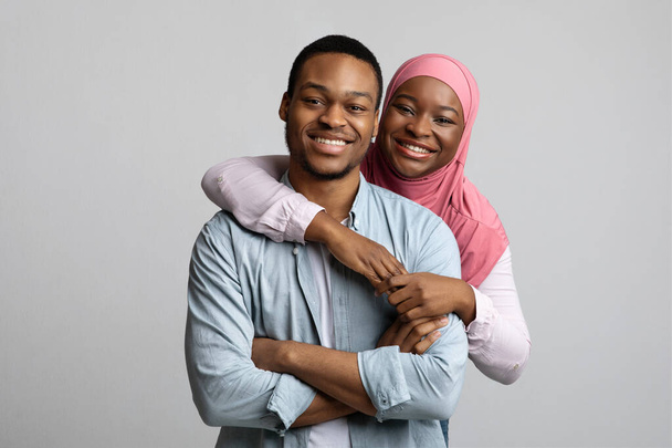 Ritratto di amorevole coppia afro-americana musulmana in posa su grigio - Foto, immagini