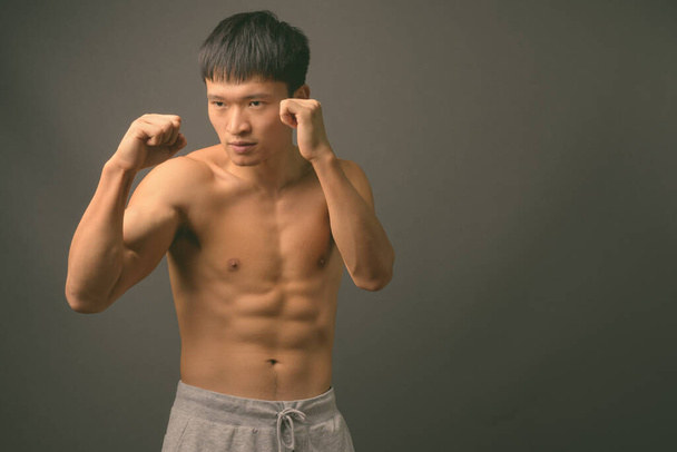 Jovem chinês sem camisa contra fundo cinza - Foto, Imagem