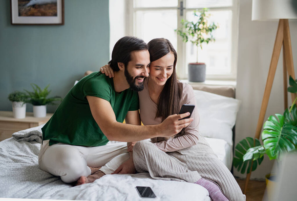 Young couple in love taking selfie on bed indoors at home. - Fotografie, Obrázek