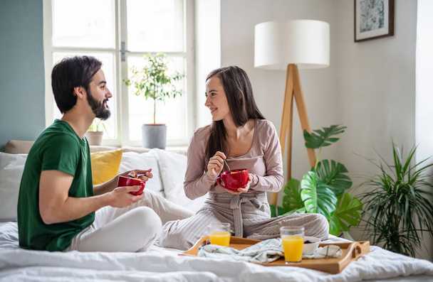 Young couple in love eating breakfast on bed indoors at home. - Photo, image