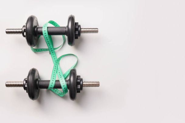Sport dumbbells and measuring tape on grey background. Top view, copy space. - Фото, зображення
