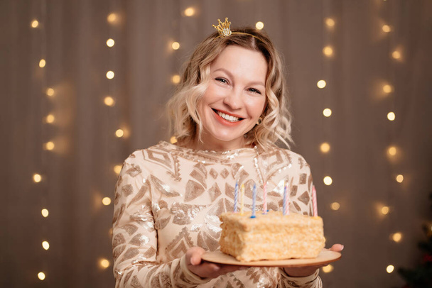Kafasında doğum günü pastası ve mumlarıyla küçük taçlı güzel sarışın kadın.. - Fotoğraf, Görsel