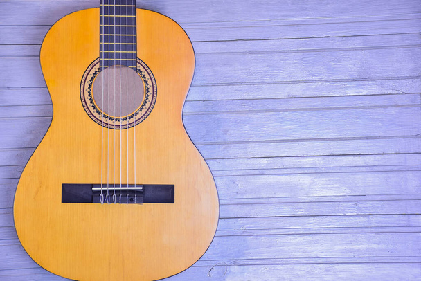 Onderdeel van een akoestische gitaar close-up op een geschilderde houten achtergrond. Er is rechts een plaats voor een inscriptie. - Foto, afbeelding