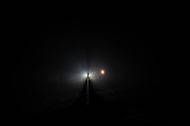 Dağlardaki sislerin içindeki ışık ışınlarının arka planındaki bir adamın silueti. - Fotoğraf, Görsel