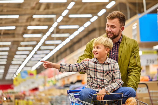 niño niño punto dedo a lado en la tienda durante las compras con el padre - Foto, imagen