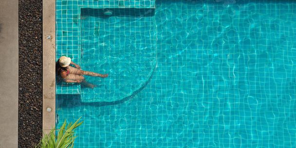 Pessoas a nadar na piscina. No verão ensolarado piscina cor azul água clara e pessoas desfrutando e ângulo de visão superior. Pessoas que relaxam no verão dia quente na piscina do hotel e ângulo de visão de pássaro - Foto, Imagem