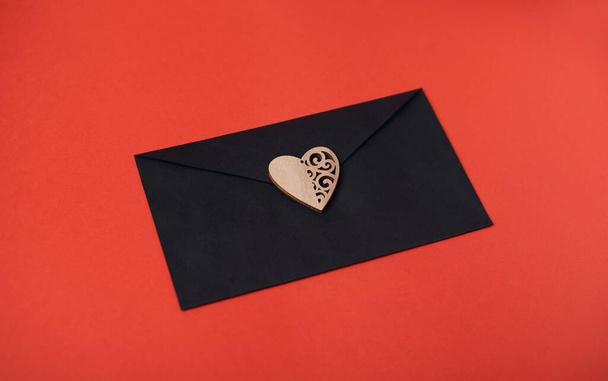 The black envelope with the red heart on the white background. Flat lay, top view. Romantic love letter for Valentine's day concept. - Fotoğraf, Görsel