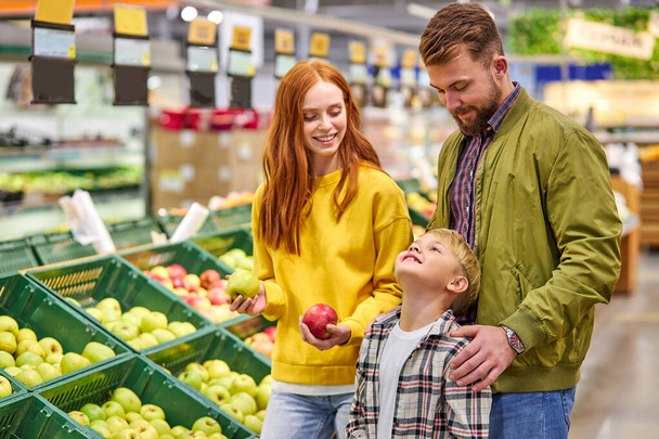 happy husband and wife with a kid buy fruits - Foto, Bild