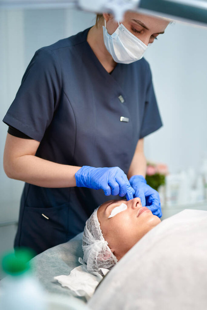 Kosmetologi lääkäri pyyhkimällä naisen kasvot käyttää puuvilla tyynyt jälkeen kuorinta Procedure.Doctor tekee kauneus menettely kosmetiikkaklinikalla - Valokuva, kuva