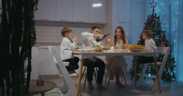 Счастливая большая кавказская семья разных поколений празднует Рождество дома. People having a dinner Xmas party eating, talking and smiling - Кадры, видео