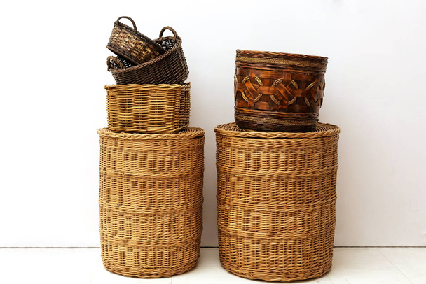 Two stacks of handmade natural wicker straw baskets for home storage of kids toys and small goods at white interior - Photo, Image