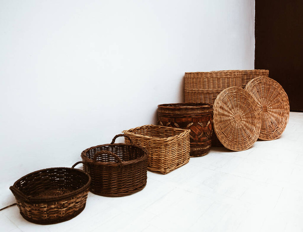 de nombreux paniers en paille d'osier et en bambou en rangée avec poignée et capuchon sur sol blanc, concept de conteneurs de rangement intérieur  - Photo, image