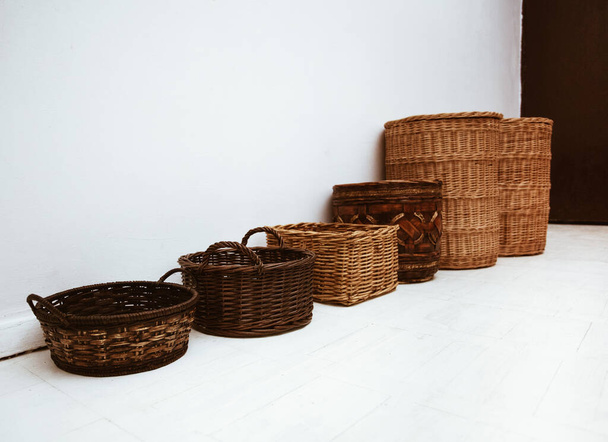 Fila de cestas de mimbre natural hechas a mano con mango y tapa, concepto de hermosos contenedores de almacenamiento en el hogar - Foto, Imagen