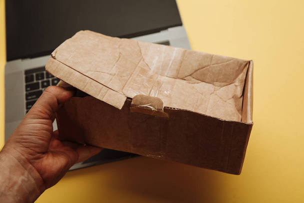 Розбита паперова коробка в руці. Концепція інтернет-магазинів і доставки. ДТП вантажу
 - Фото, зображення