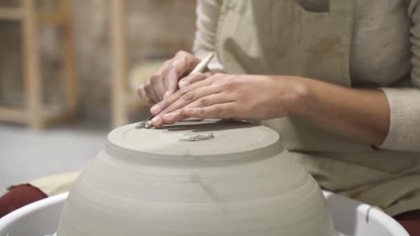 Primo piano di una donna artigiana seduta alla scrivania nel laboratorio di ceramica e che lavora su una ciotola di argilla. - Filmati, video
