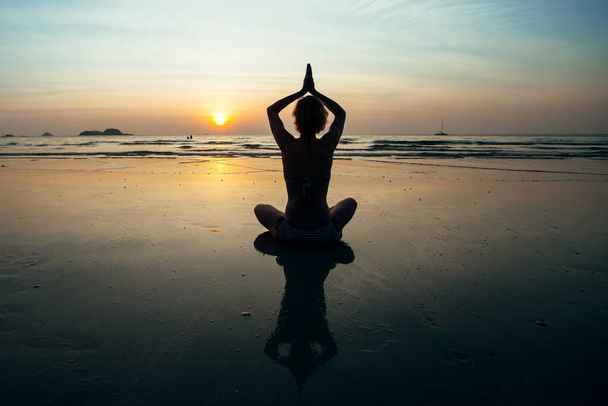 Meditazione donna yoga sulla costa del tramonto con riflessione in acqua. - Foto, immagini
