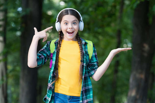 Happy kid point finger at modern headphones holding open hand, presenting product, copy space - Φωτογραφία, εικόνα