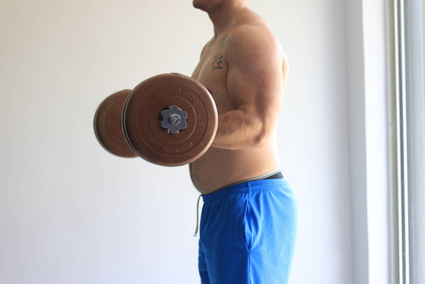 El hombre hace rizos de bíceps adentro. Foto de alta calidad - Foto, imagen