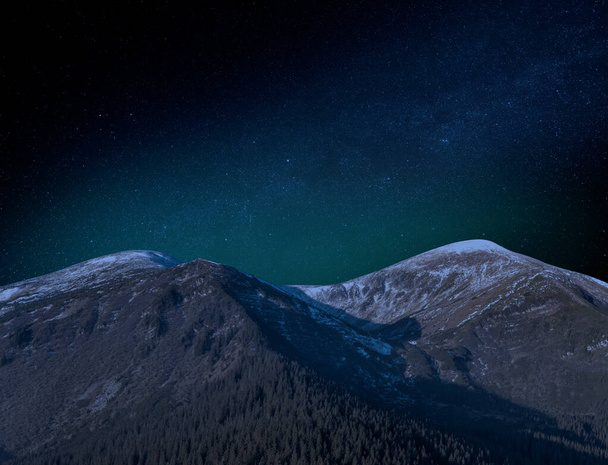 Starry sky over the tops of partially snow-capped mountains. Picturesque night landscape. - Photo, Image