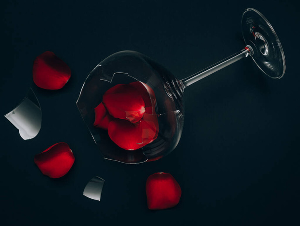 Broken glass and rose petals with fringes lie diagonally on a black background, top view. - Foto, imagen