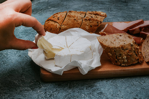 Baguette with sesame seeds and seeds, dark bread with camembert and meat on a board. Meat and cheese snack, breakfast. Nice photo of food. Snack delivery. - 写真・画像